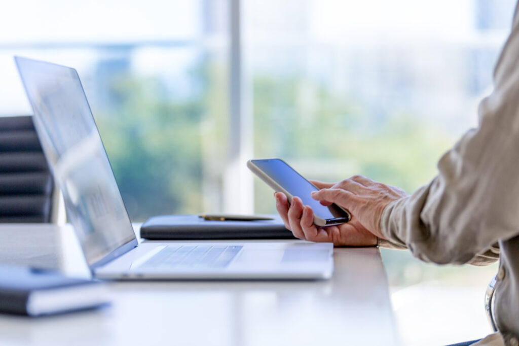 Close up of a businessman using a laptop computer and a mobile phone.