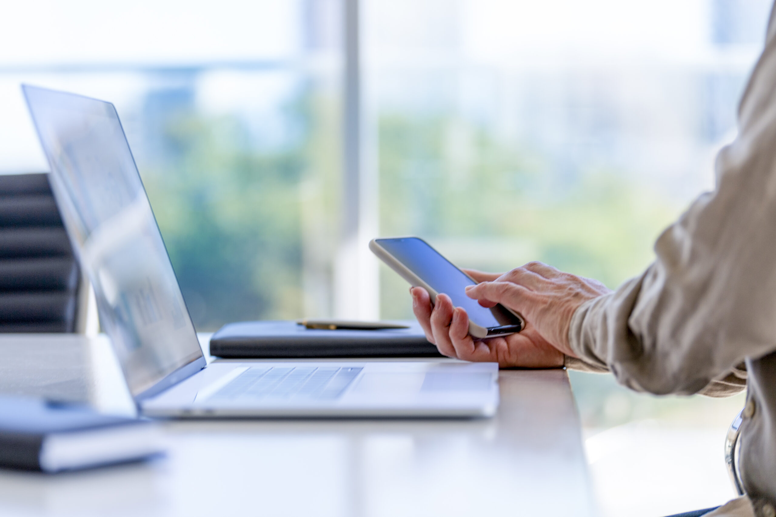 Close up of a businessman using a laptop computer and a mobile phone.